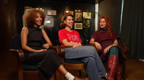 Raye and her sisters Lauren (left) and Abby-Lyn (right) speak to BBC News backstage at the Graham Norton Show in September 2025