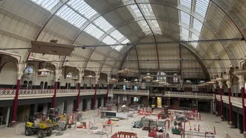 Work going on inside the market hall. Workers and piles of paving slabs can be seen as well as a small machine.