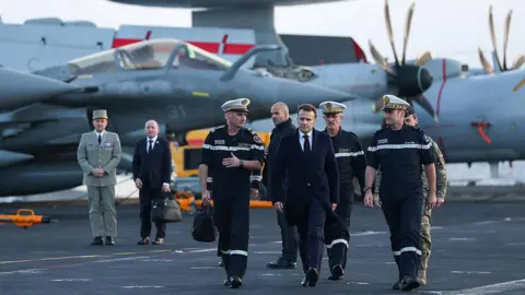 AFP via Getty Images French President Emmanuel Macron (C) visits the French aircraft carrier Charles de Gaulle