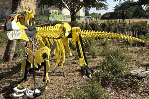 Blenheim Palace A yellow and black Megalosaurus sculpture on all fours.