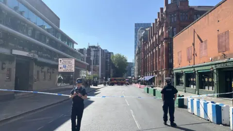 Police officers stand by a cordon on Peter Street.