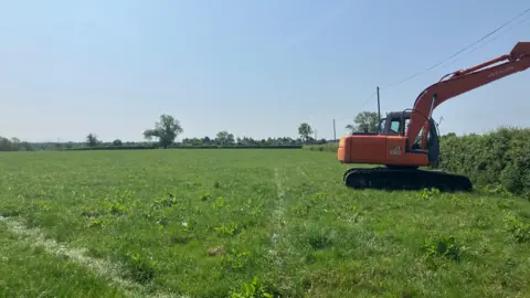 An orange digger within a field.