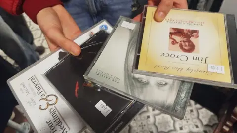 Paul Burnell/BBC Three CDs and a DVD in the hands of a customer at a charity shop. 