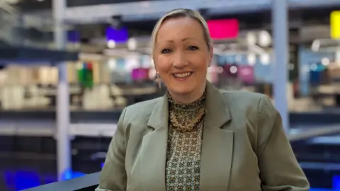 Rebecca Evans, Cabinet Secretary for Economy, Energy and Planning, smiling to the camera and stood in a BBC building.