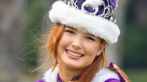 Berwick Town Council A close-up image of a young woman with red hair wearing a purple gown and crown. 