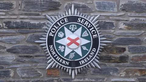 A PSNI logo on a brick wall