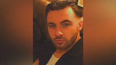 Contributed What appears to be a selfie of Chas Corrigan's face. He has slicked-back hear and a full, short beard. He is sitting on padded seating. He is wearing a black short-sleeved shirt over a white T-shirt