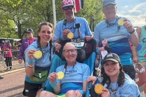 David, Alice and three others pose with their medals at the London Marathon finish line.