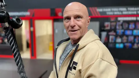 BBC Charles Tweed in a hooded top at his gym