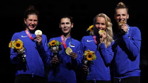 Estonia's women's épée team pose with their medals. They are smiling at the camera. 