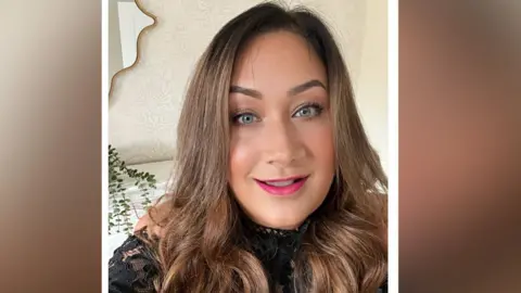 Janie Tongue A headshot selfie of Janie, who smiles at the camera. She wears pink lipstick and has dark blonde, long wavy hair.