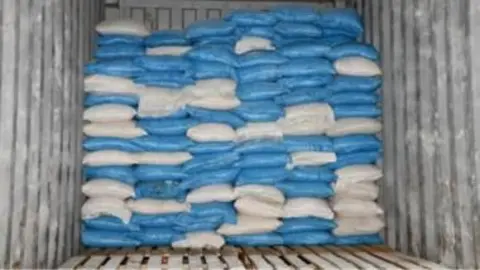 National Crime Agency Bllue and white clingwrapped bags of cocaine in the bottom of a large trailer. 