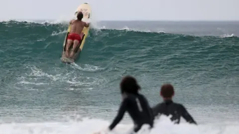 Reuters An RNLI Lifeguard uses a rescue board during hot weather at Perranporth beach, in Perranporth, Cornwall