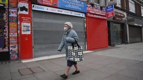 EPA A woman walking down an empty street in London