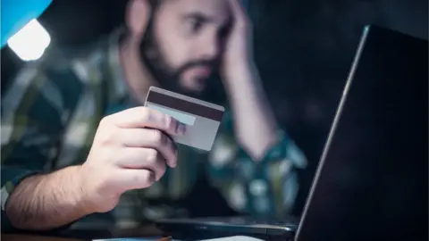 Getty Images/domoyega Close-up of a man paying bills using a laptop and a credit card - stock photo