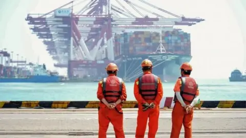 AFP Dock workers in China watch a container ship