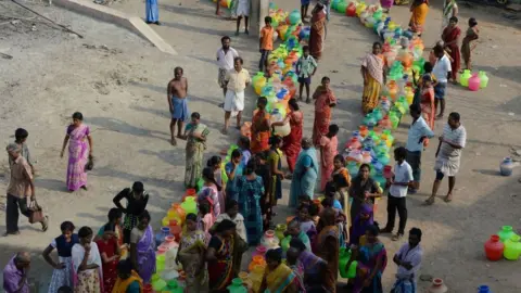 Getty Images Indian residents queue with plastic recipients to get drinking water from a distribution tanker in the outskirts of Chennai on May 29, 2019.