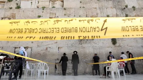 EPA Jews pray in an area restricted to 10 people at the Western Wall in Jerusalem (16 March 2020)
