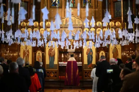 DANIEL LEAL/AFP Bishop of the Ukrainian Catholic Church of London Kenneth Nowakowski (c) conducts the ecumenical prayer service at Ukrainian Catholic Cathedral, in London, on 24 February 2023,