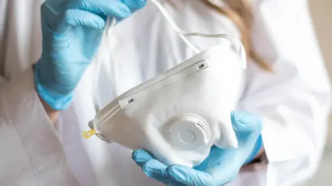 Getty Images Mask held in gloved hands