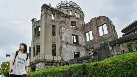A woman walks past the Atomic Bomb Dome in the centre of Hiroshima