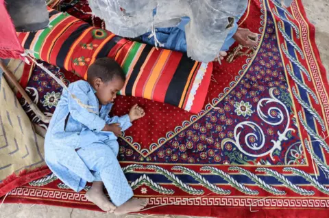 AFP A boy takes a nap while lying on a carpet and sheltering from the sun.