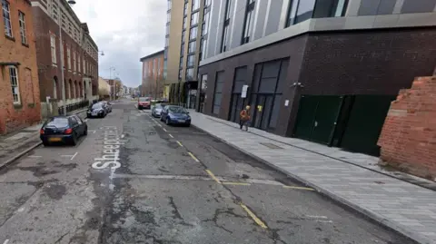 Google A generic image of Sheepcote Street showing buildings and parked cars on both sides of the road. A man is walking on the pavement to the right.