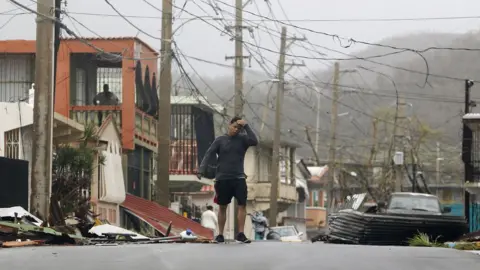 Getty Images A man reacts as he walks through a debris-covered road in Fajardo, Puerto Rico.