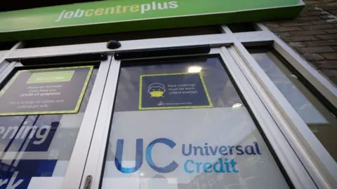 PA Media Universal Credit sign on the door of a job centre plus in east London