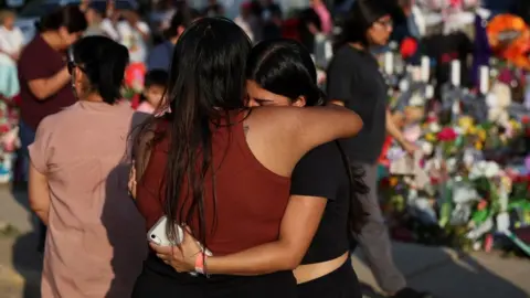 Reuters Women embrace at a memorial to those killed in the Uvalde mass shooting