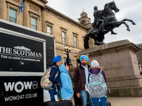 Peter Dench A family on holiday from India at the northern end of the A! at the junction of North Bridge and Princes Street. Edinburgh.