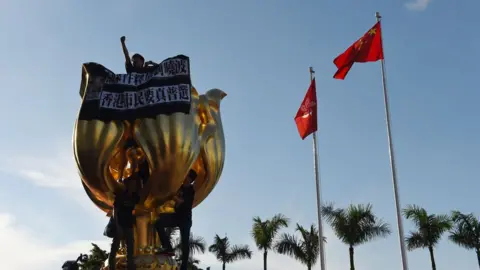 AFP Activists on the monument given by China to Hong Kong in 1997