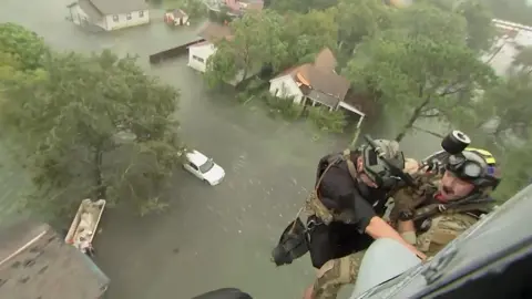 Reuters Two rescuers from US Navy Helicopter Sea Combat Squadron 7 are lowered to a house after Tropical Storm Harvey flooded a neighbourhood in Beaumont, Texas, 30 August