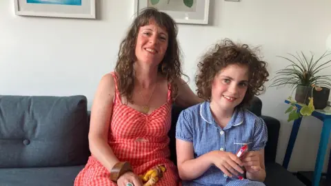 BBC A mum in a red dress and a young child in her school uniform