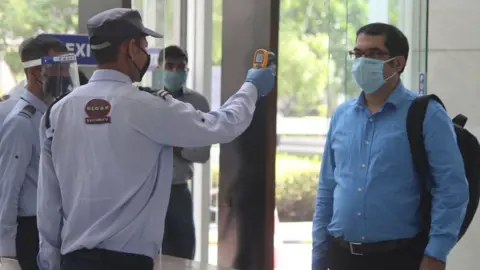 Getty Images A security guard thermal screens people as they enter an office building at Park Centra in Sector 30, on June 8, 2020 in Gurugram, India.