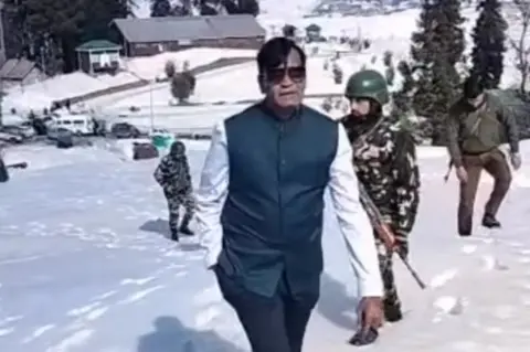 Kiran J Patel/Twitter A screenshot from a video showing Patel with a security cover in Gulmarg