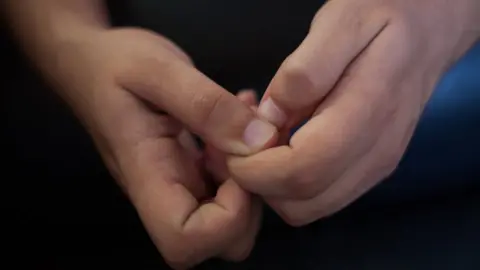 Getty Images Close-up, teenage boy clasps hands