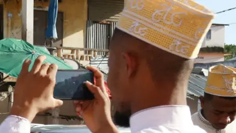 AFP A Comorian man in a kofia hat taking a photo