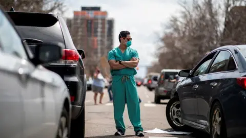 Alyson McClaran Protests against virus shutdowns in Denver on 19, April meet two counter-protesters dressed as healthcare workers