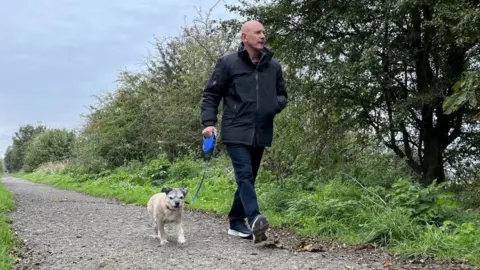 BBC A man walking his dog in the countryside