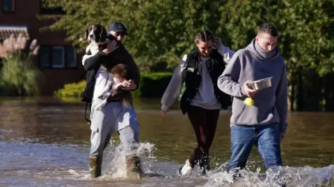 PA Media Residents walk through flood water in Retford in Nottinghamshire