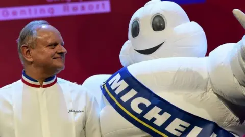 AFP Joel Robuchon (L) stars poses with the tyre company's mascot during the Michelin Guides Award ceremony in Singapore on 21 July 2016