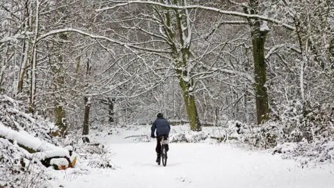 Getty Images A man cycles across snow-covered Hampstead Heath in 2008