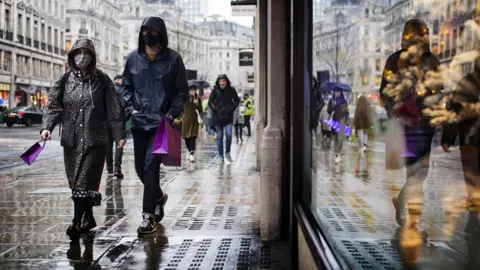 PA Media Shoppers in a wet London street