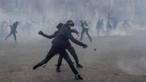 AFP Demonstrators throw cobblestones at riot police forces during clashes near the Arc de Triomphe in Paris on March 16, 2019