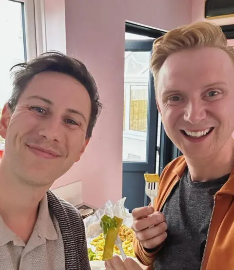 Owain Wyn Evans / Instagram Owain and Aaron eating a bag of chips