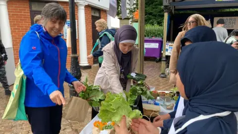 Alex Pope/BBC People purchasing items from the children on Bedford Market 