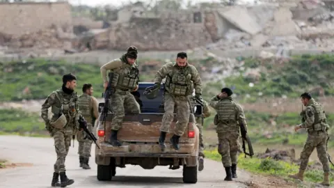 Reuters Turkish-backed Syrian rebel fighters in Maryamayn, in the eastern Afrin region (11 March 2018)