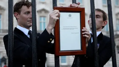 Reuters Buckingham Palace staff place the official notice of the Queen's death outside the palace