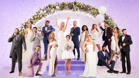 Channel 4 The cast of MAFS UK 2023 - a mix of the 16 contestants made up of eight grooms wearing suits and eight brides in white dresses. The cast are pictured on a purple background with confetti and a floral wedding arch